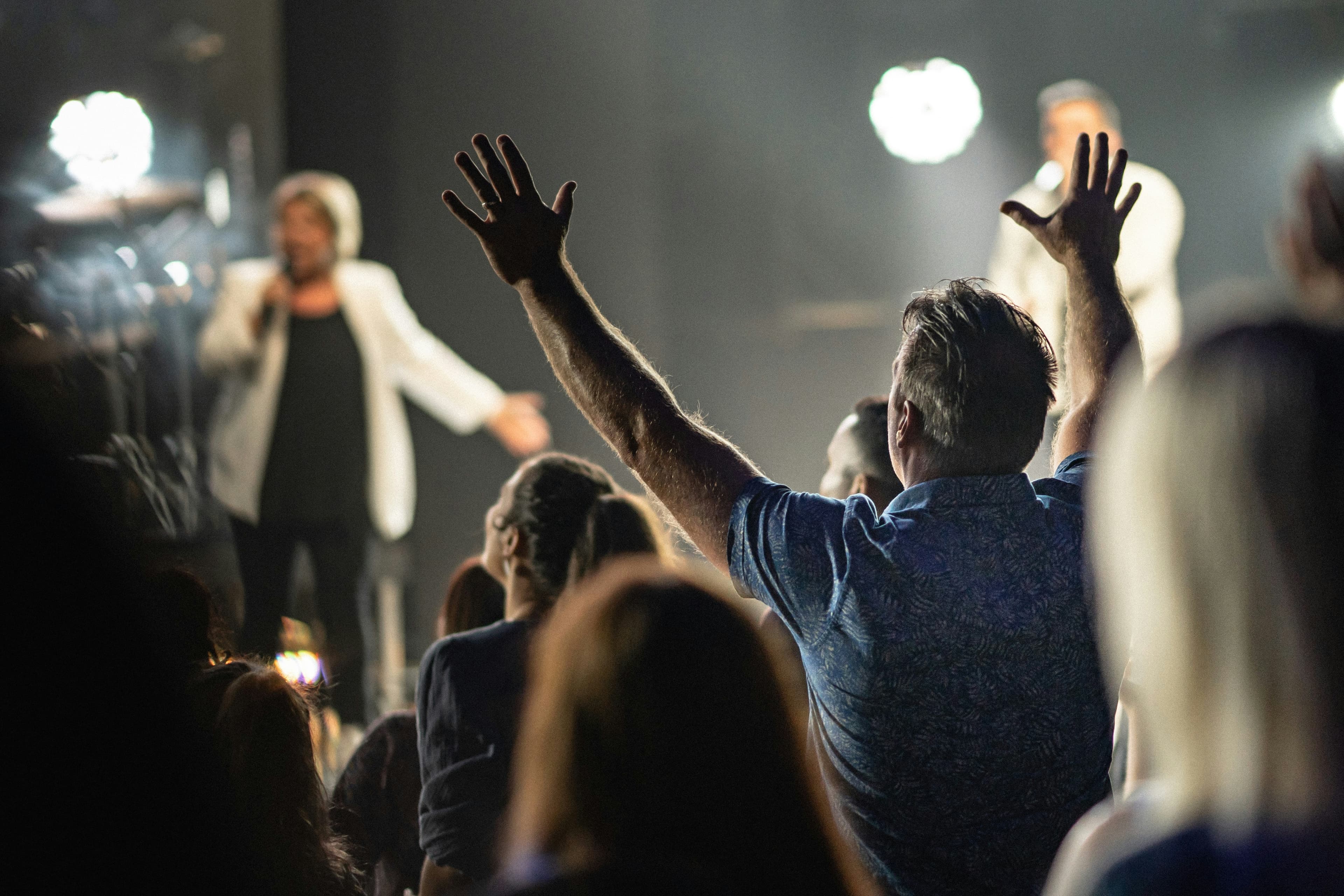 Congregation members worshipping with hands raised during a church service